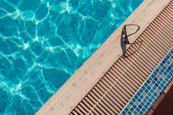 Gafas de natación junto al borde de una piscina azul
